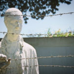 Why Does Power Corrupt? - Weekly Blog Post by Dr. Craig Biehl - statue of man behind barbed wire in a concentration camp