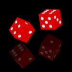 Random Chance Behind an Ordered Universe? - Weekly Blog Post by Dr. Craig Biehl - Red dice with reflection on black